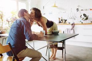 Pareja madura besándose sobre la mesa del desayuno.