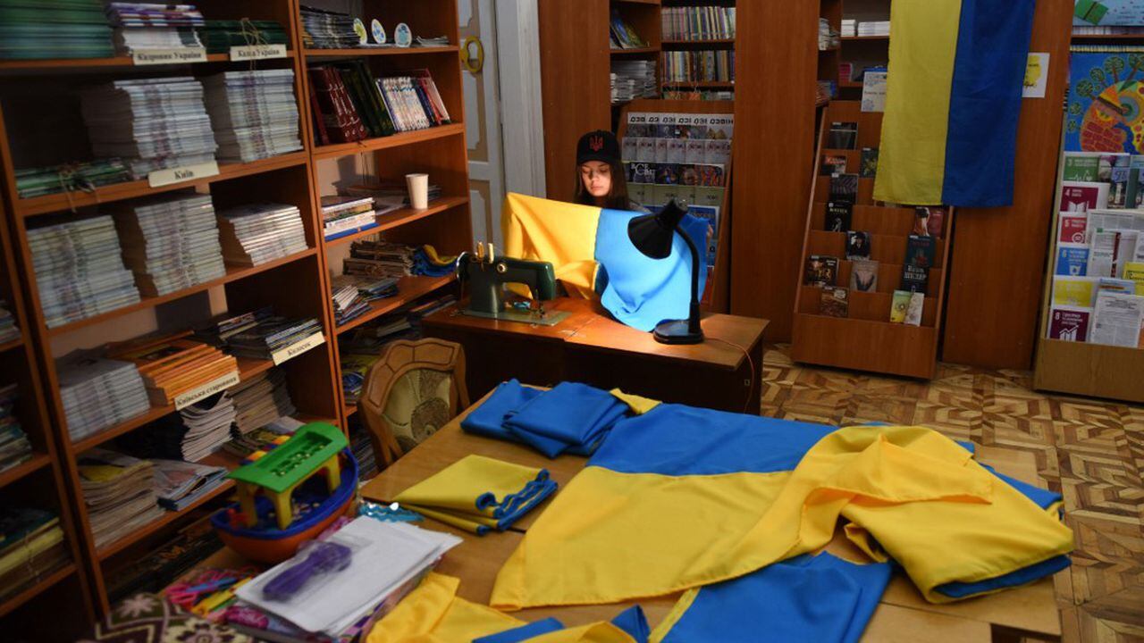 Un joven voluntario cose banderas ucranianas para el ejército ucraniano en una biblioteca en la ciudad de Lviv, en el oeste de Ucrania, el 2 de abril de 2022. (Foto de Yuriy Dyachyshyn / AFP)