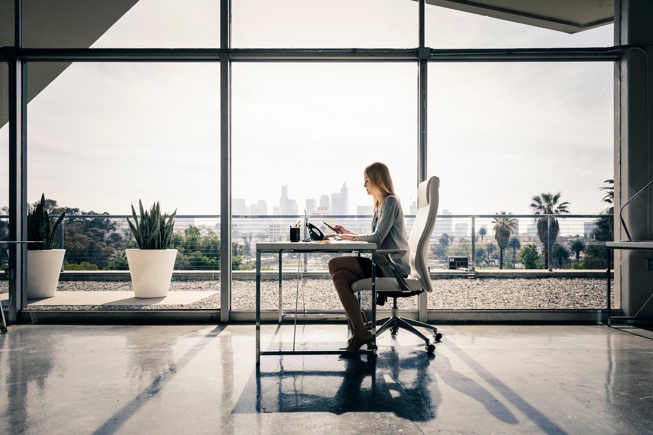 Vista lateral de una empresaria sentada en un escritorio trabajando en la oficina