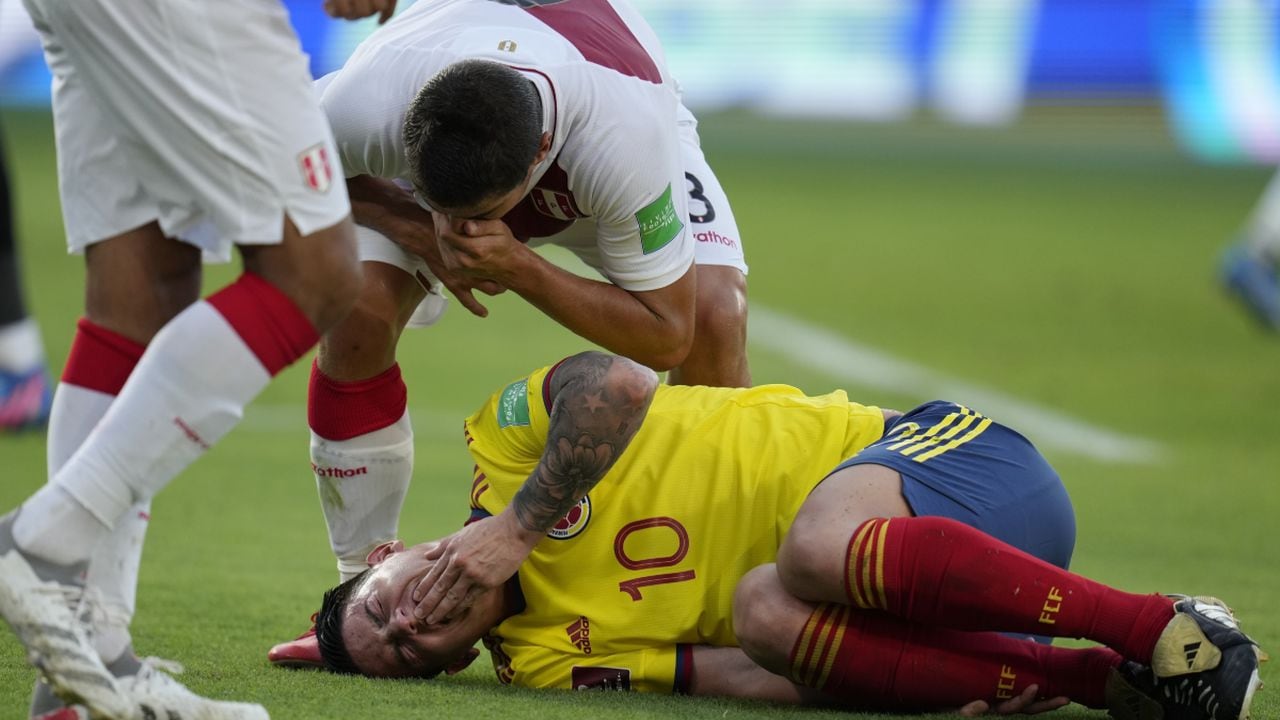 Peru's Aldo Corzo taunts Colombia's James Rodriguez after falling on the pitch during a qualifying soccer match for the FIFA World Cup Qatar 2022 at the Roberto Melendez stadium in Barranquilla, Colombia, Friday, Jan. 28, 2022. (AP/Fernando Vergara)