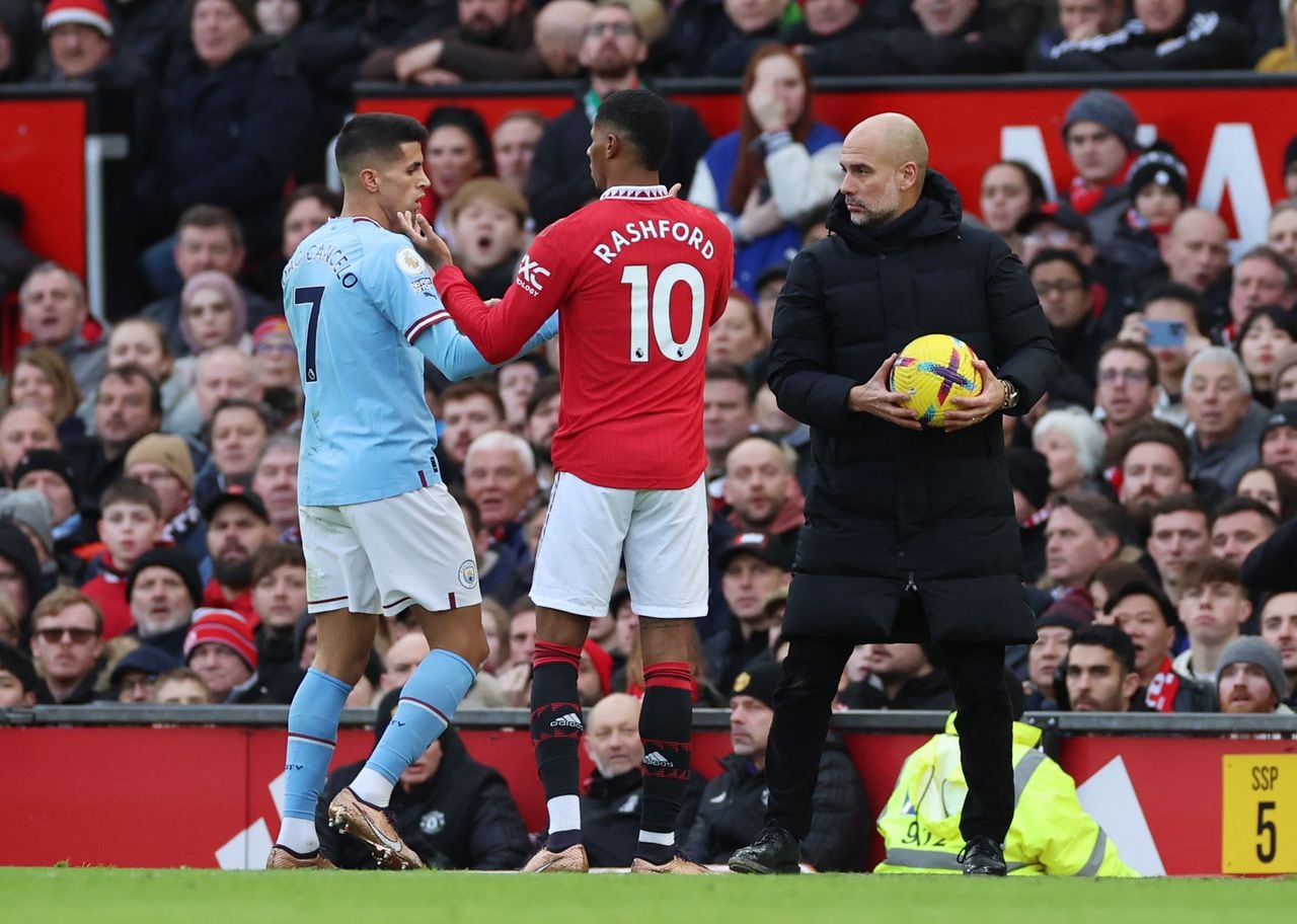 Soccer Football - Premier League - Manchester United v Manchester City - Old Trafford, Manchester, Britain - January 14, 2023 Manchester City's Joao Cancelo and Manchester United's Marcus Rashford react as Manchester City manager Pep Guardiola looks on REUTERS/Phil Noble EDITORIAL USE ONLY. No use with unauthorized audio, video, data, fixture lists, club/league logos or 'live' services. Online in-match use limited to 75 images, no video emulation. No use in betting, games or single club /league/player publications.  Please contact your account representative for further details.