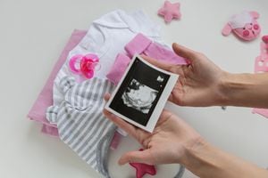 Mujer embarazada sostiene ecografía en la que se revela el sexo de su bebé.