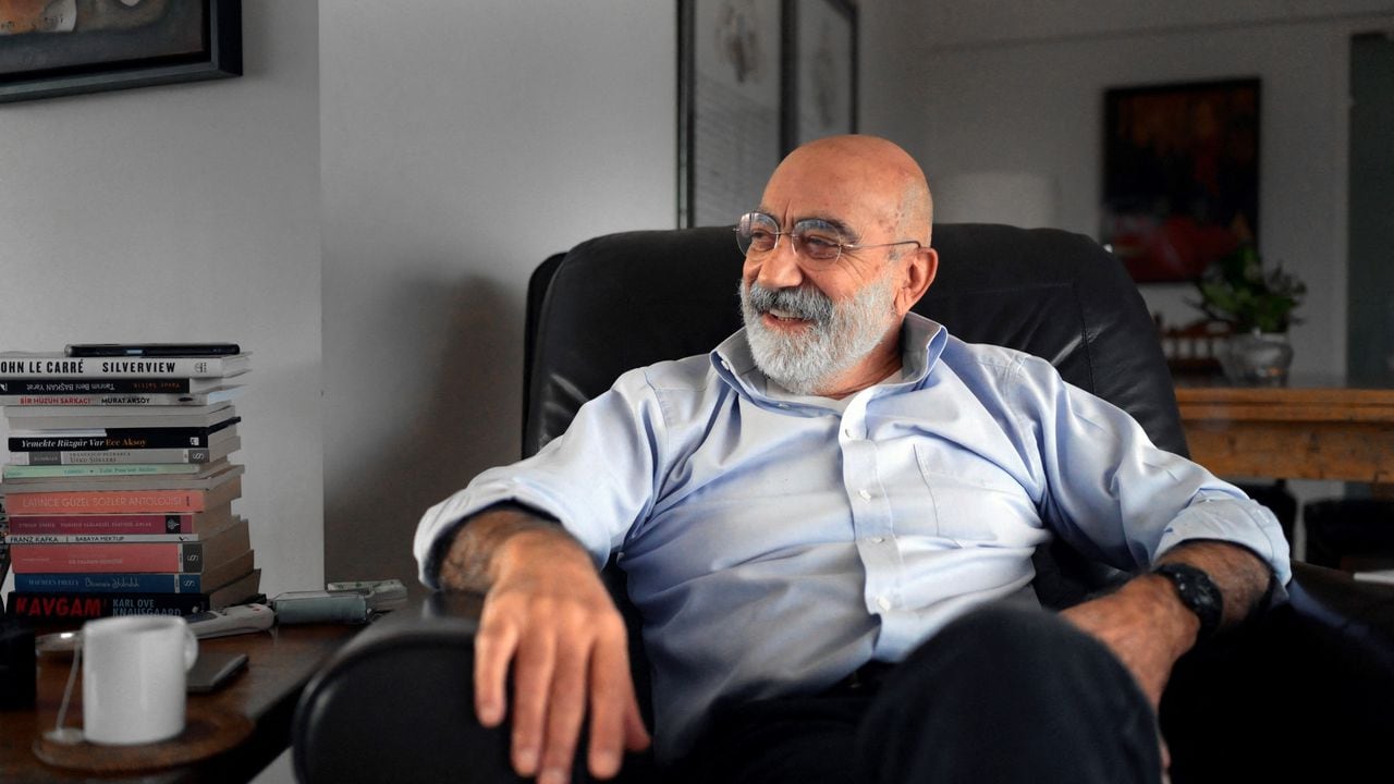 El escritor y periodista turco Ahmet Altan sonríe durante una entrevista en su apartamento en Estambul, en enero de 2022. Recién liberado, tras cinco años de prisión por su supuesto involucramiento en un fallido golpe de Estado, a sus 71 años ahora cuenta el tiempo en los libros que falta escribir. Foto: BULENT KILIC / AFP.