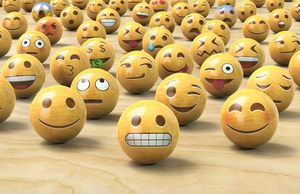 Muchos emoticonos de madera o bolas de cara de Emoji, una al frente