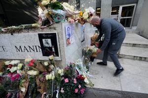 Un hombre coloca flores frente al edificio donde se descubrió el cuerpo de una niña de 12 años en un baúl, en París, el miércoles 19 de octubre de 2022. Francia está "profundamente conmocionada" por el asesinato de una niña de 12 años. (AP Photo/Michel Euler)