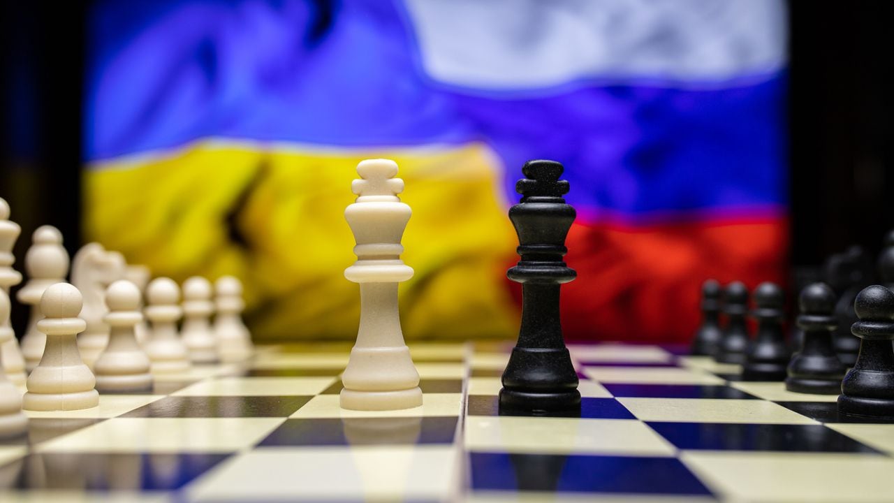 Guerra entre Rusia y Ucrania, imagen conceptual usando tablero de ajedrez, piezas y banderas nacionales en el fondo