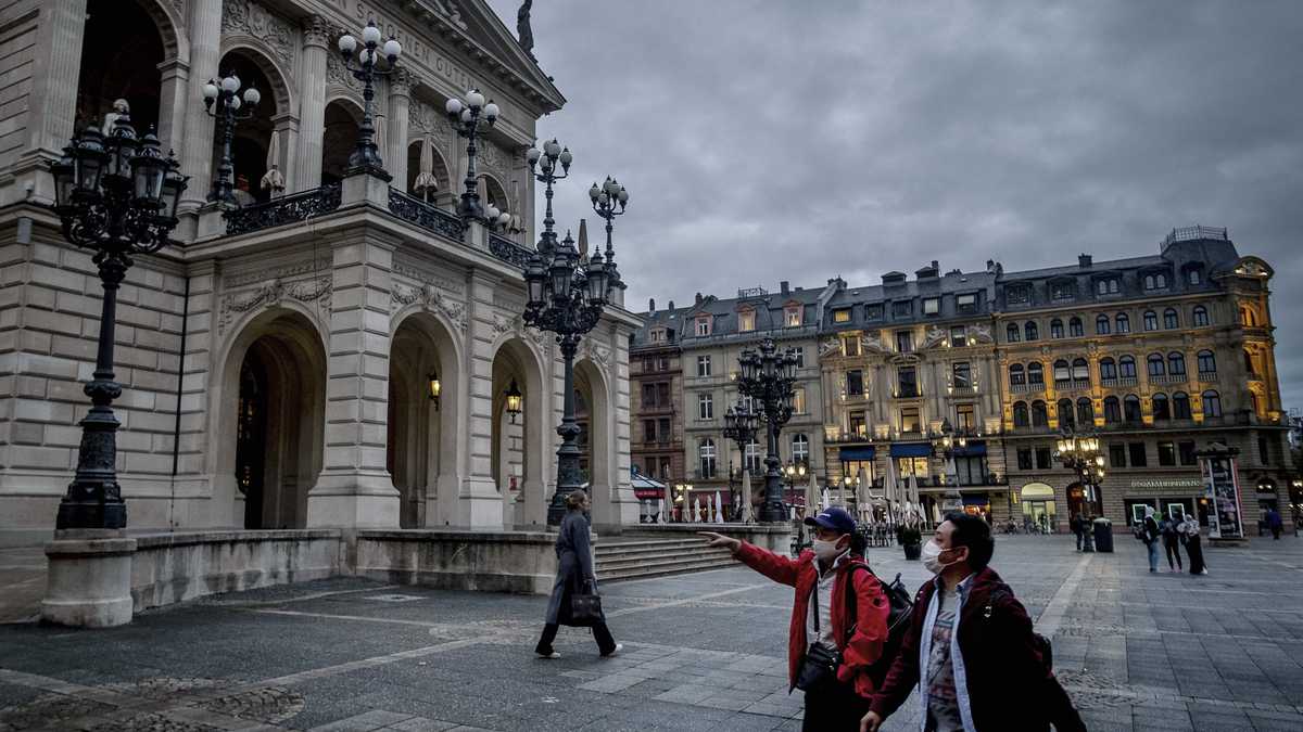 Dos personas con tapabocas caminan al frente de la Opera de Frankfurt, Alemania.