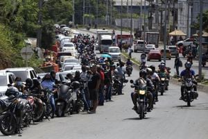 Drivers and motorcyclists wait their turn to fill up at a gas station in Cali, Colombia, Friday, May 7, 2021. Protesters are blocking the main roads as a part of anti-government protests that has resulted in cities having a shortage of food and fuel. (AP Photo/Andres Gonzalez)