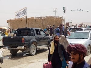 Personas que llegan de Afganistán caminan mientras las banderas de Pakistán y los talibanes se ven al fondo, en el cruce de la Puerta de la Amistad en la ciudad fronteriza entre Pakistán y Afganistán de Chaman, Pakistán, el 17 de agosto de 2021. REUTERS / REUTERS / Abdul Khaliq Achakzai NO RESALES. SIN ARCHIVO