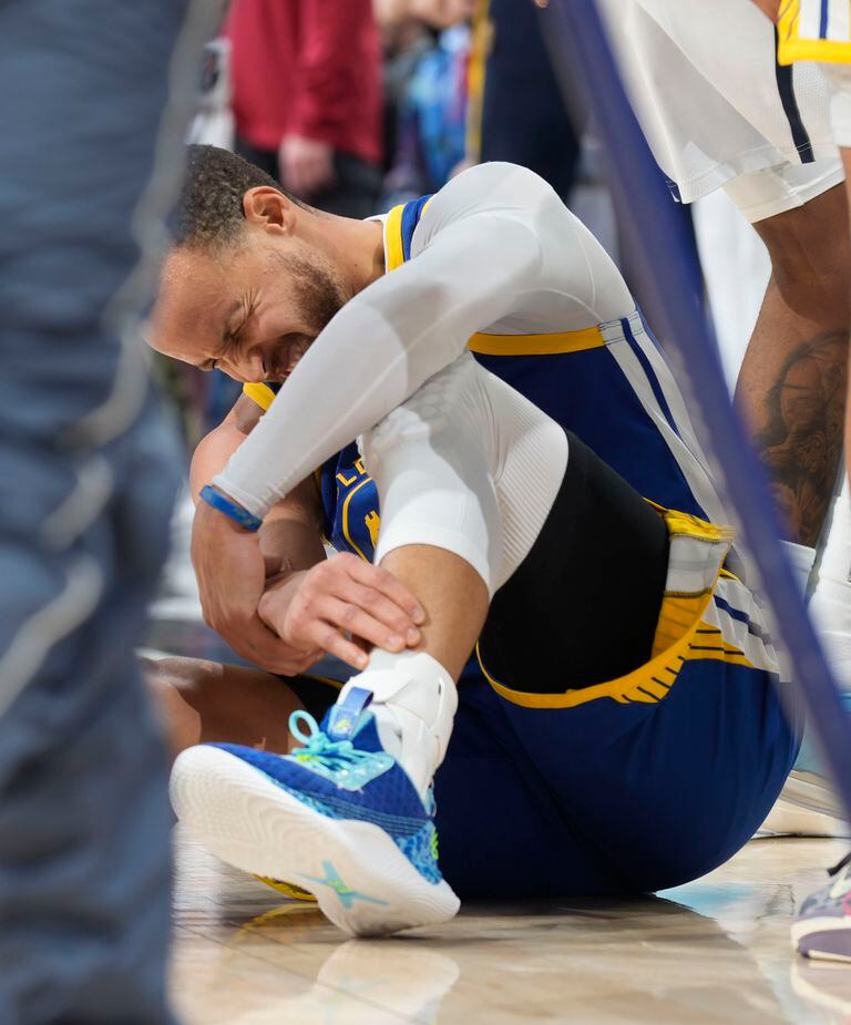 Golden State Warriors guard Stephen Curry grabs his left leg after he was fouled while making a 3-point basket by Denver Nuggets forward Zeke Nnaji in the second half of an NBA basketball game Thursday, Feb. 2, 2023, in Denver. Curry remained in the game. (AP Photo/David Zalubowski)