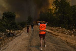 Unas personas corren lejos del poblado de Sirtkoy, en Antalya, Turquía, el domingo 1 de agosto de 2021, luego de que fue devastado por un incendio forestal. (AP Foto)