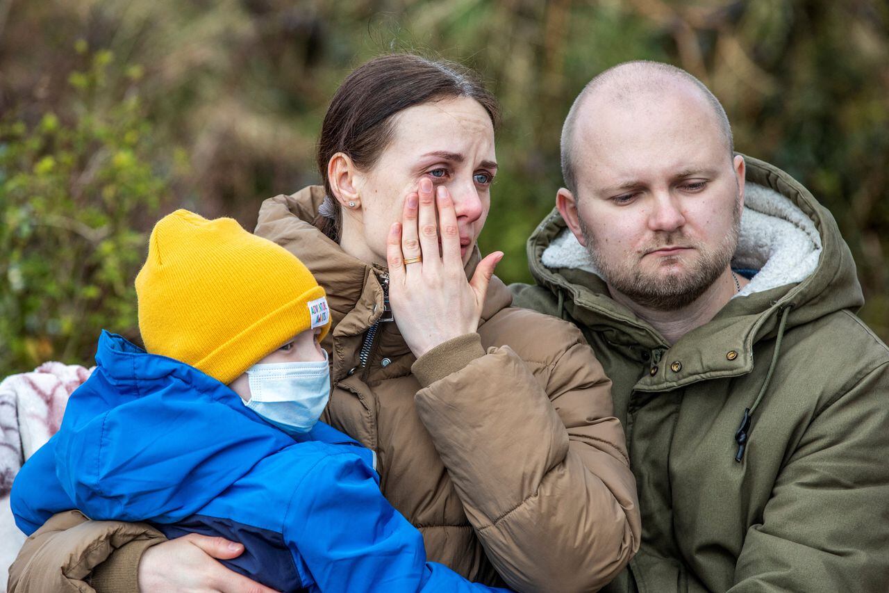 Yana (L) and Serhiy Shapoval (R) speak during an interview with AFP, with their five-year-old son Leonid, who suffers from leukaemia, in front of their new home in Ballydehob, near Cork, south west Ireland, on March 7, 2022 after fleeing Ukraine following Russia's invasion of the country. - The Shapovals escaped the war in Ukraine after doctors urged the parents of Leonid to leave the country on March 3, 2022, telling them there was no more they could do for their son. Yana and Serhiy have since learnt that the hospital, where Leonid received his chemotherapy in Kyiv, has been bombed by Russian forces. Five-year-old Leonid is now being treated in Ireland for his condition. (Photo by PAUL FAITH / AFP)