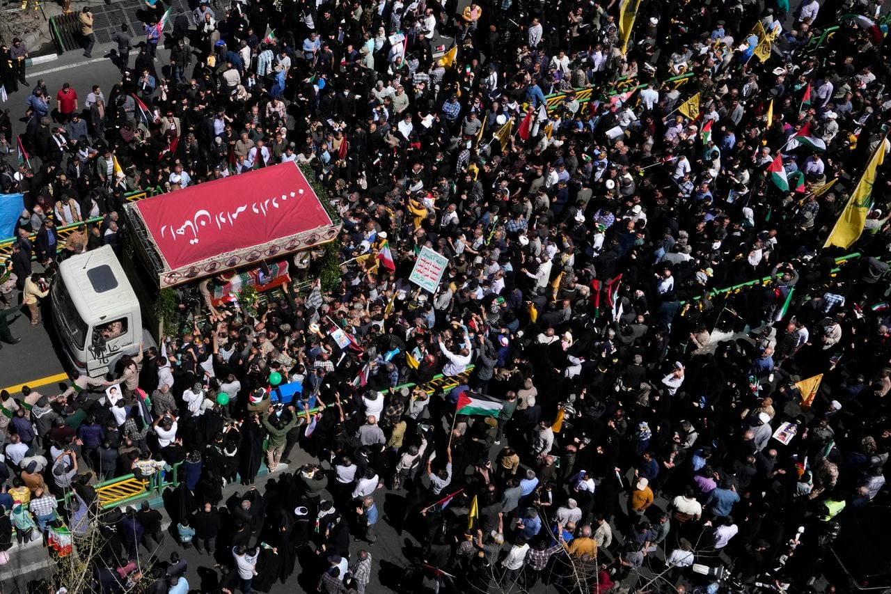 Miles de iraníes rodean el camión que traslada los ataúdes de los integrantes de la Guardia Revolucionaria que murieron en un ataque aéreo atribuido a Israel que destruyó la sección consular de la embajada iraní en Siria el lunes, en un cortejo fúnebre en Teherán, Irán, el viernes 5 de abril de 2024. (AP Foto/Vahid Salemi)