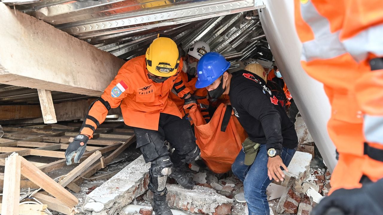 Rescatistas sacan a un herido debajo de un edificio derrumbado por el terremoto en Indonesia.