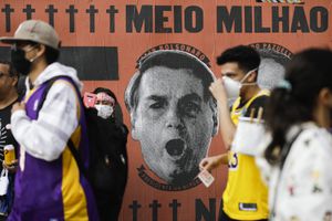 Manifestantes caminan frente a un mural que representa el rostro del presidente brasileño Jair Bolsonaro durante una manifestación contra el manejo de Bolsonaro de la pandemia de coronavirus y las políticas económicas.  (AP Photo/Marcelo Chello)