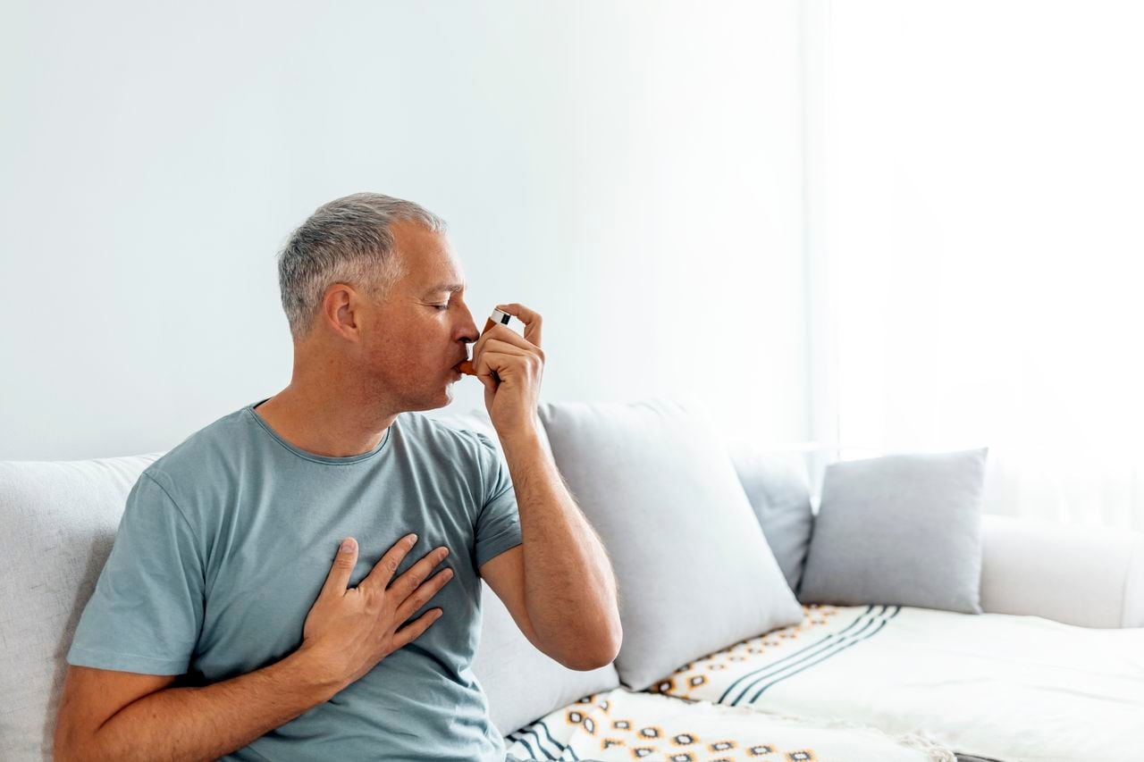 Hombre maduro, el tratamiento del asma con inhalador en casa