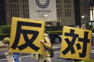 Personas en contra de la apertura en julio de los Juegos Olímpicos de Tokio 2020 sostienen una pancarta que dice "oposición" en japonés mientras marchan alrededor del edificio del Gobierno Metropolitano de Tokio durante una manifestación el miércoles 23 de junio de 2021 en Tokio. Foto: AP / Eugene Hoshiko.
