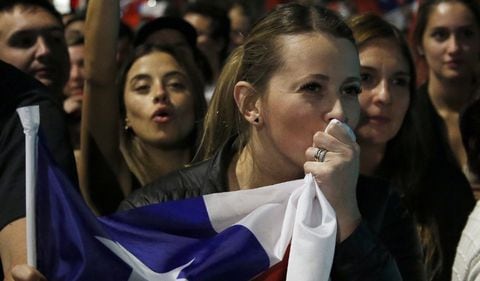 Una mujer celebra en Chile haya ganado el NO a la nueva constitución y besa la bandera del país