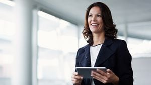 Mujer de negocios feliz mirando hacia otro lado mientras sostiene una tableta digital en la oficina