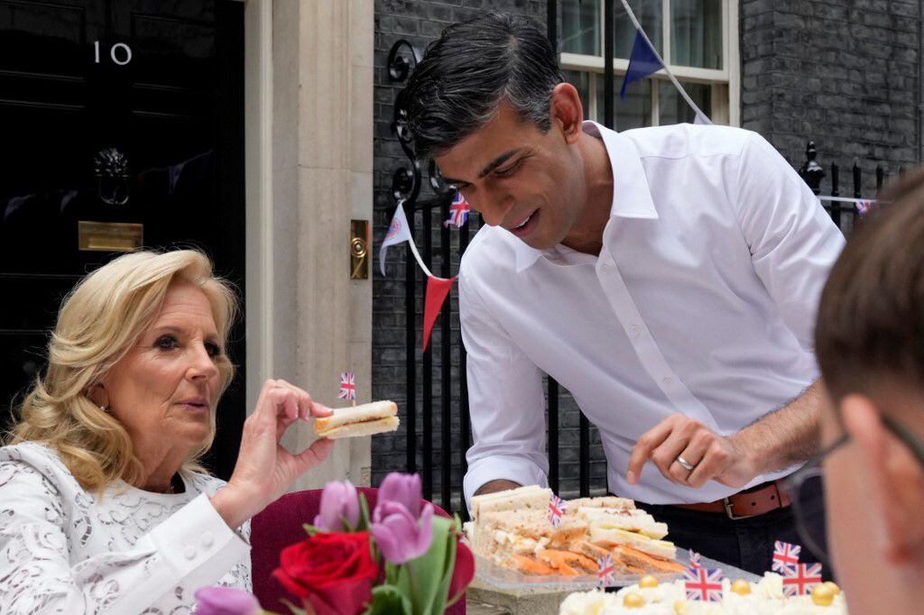 El primer ministro británico, Rishi Sunak (derecha), le muestra sándwiches a la primera dama de los Estados Unidos, Jill Biden, durante un gran almuerzo de coronación organizado en Downing Street, Londres, el 7 de mayo de 2023.