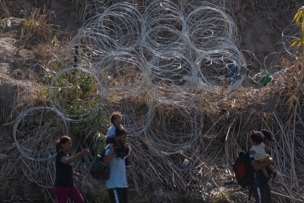 Migrantes caminan a lo largo de la orilla del río Grande mientras buscan una abertura en el alambre de concertina mientras intentan ingresar a Eagle Pass, Texas, EE. UU. 27 de julio de 2023.