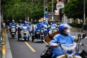 Trabajadores con trajes protectores montan triciclos y scooters eléctricos durante el encierro, en medio de la pandemia de la enfermedad por coronavirus (COVID-19), en Shanghái, China, el 30 de abril de 2022. Foto REUTERS/Aly Song