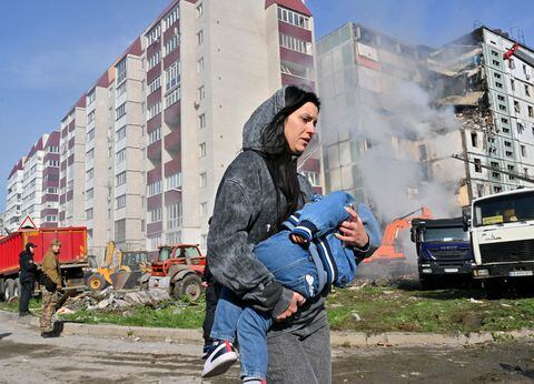 Una mujer pasa junto a edificios residenciales dañados mientras lleva a un niño en Uman, a unos 215 km al sur de Kiev. Foto: AFP