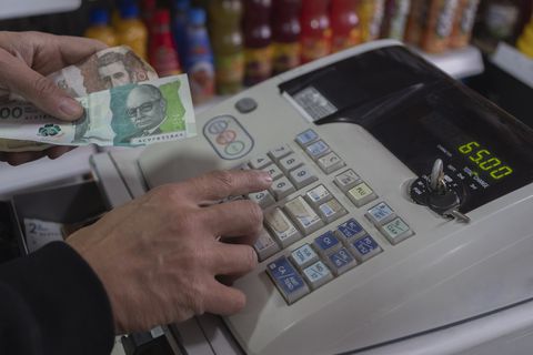 Colombian money, pesos, in hand in a cash register . concept of economics