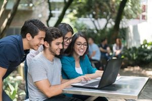Retrato de un feliz grupo de estudiantes de la universidad usando una computadora portátil mientras estudian al aire libre - conceptos educativos