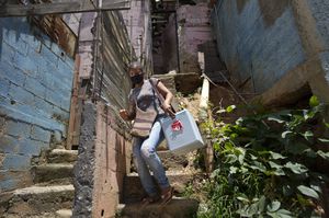 Un trabajador de salud que lleva una hielera que contiene dosis de la vacuna Sinopharm baja las escaleras durante las vacunaciones casa por casa en el popular barrio de El Valle en Caracas, Venezuela, el lunes. 27, 2021. (AP Photo/Ariana Cubillos)