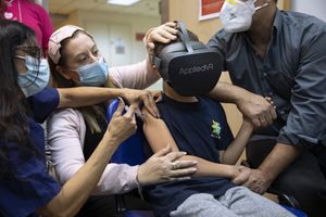 El niño israelí Rafael Peled, de 8 años, mira a través de unas gafas de realidad virtual mientras recibe una vacuna Pfizer-BioNTech COVID-19 del personal médico en el Hospital Sheba Tel Hashomer en Ramat Gan, Israel, el lunes 22 de noviembre de 2021. Israel tiene aprobó la vacuna contra el coronavirus para niños de 5 a 11 años. Foto AP / Oded Balilty