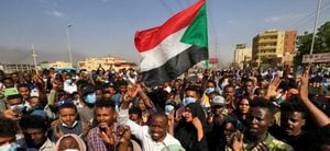 Los manifestantes sudaneses levantan banderas nacionales mientras se manifiestan en la calle 60 en la capital, Jartum, para denunciar las detenciones nocturnas por parte del ejército de miembros del gobierno, el 25 de octubre de 2021.