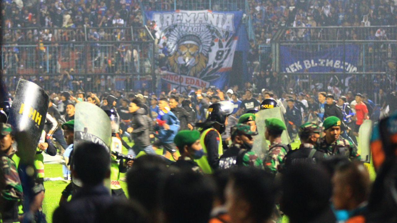 MALANG, INDONESIA - OCTOBER 01: Football supporters enter the pitch as security officers try to disperse them during a riot following a soccer match at Kanjuruhan Stadium in Malang, East Java, Indonesia, 01 October 2022. According to government officials, at least 174 people including police officers were killed mostly in stampedes after riots following a soccer match. (Photo by Suryanto/Anadolu Agency via Getty Images)