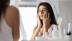 Anti-Wrinkle Skincare. Sad Young Woman Touching Face Looking At Her Skin In Mirror At Bathroom. Selective Focus, Panorama