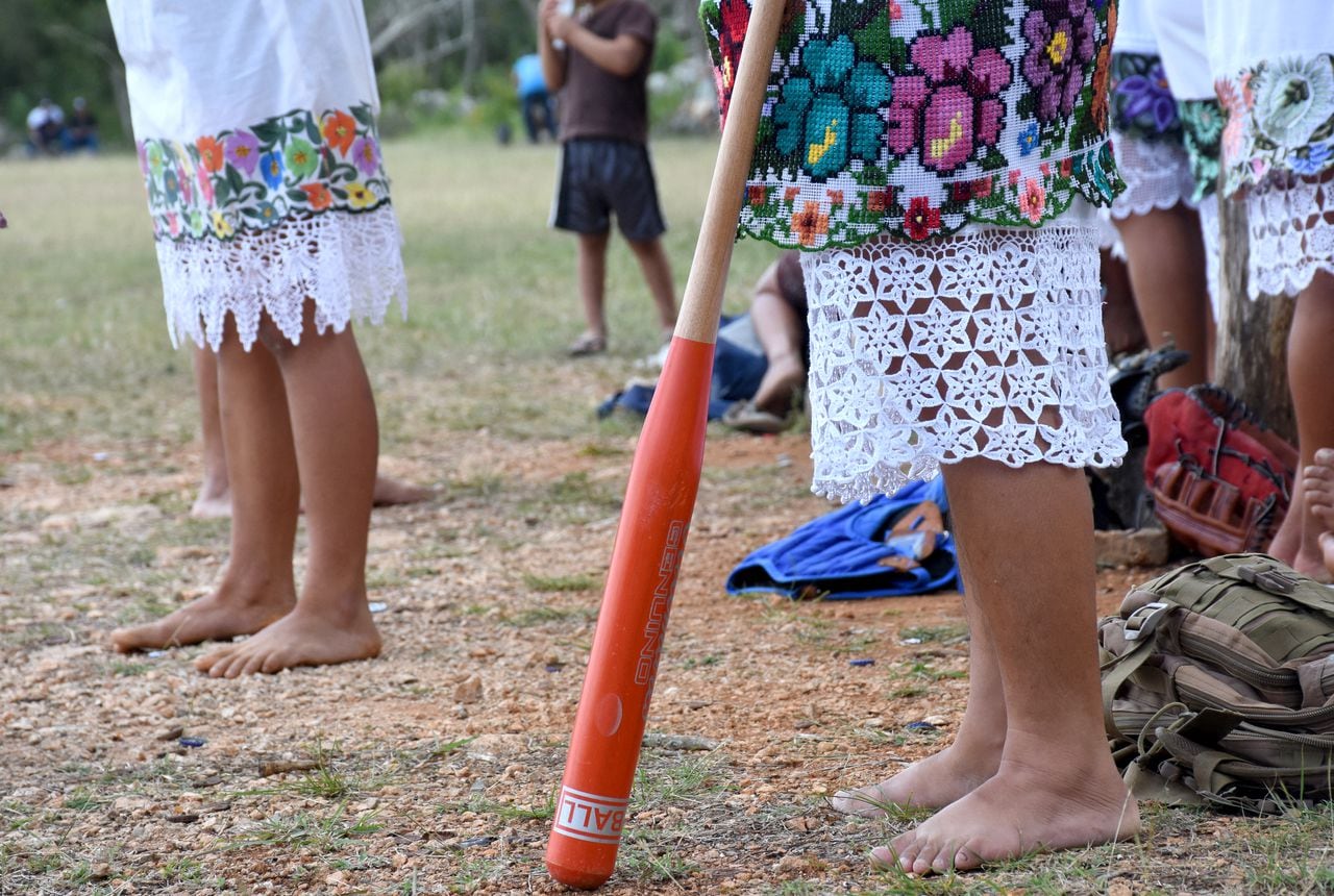 Players of "Las Diablillas de Hondzonot", wait for their turn to play during a softball match against "Guerreras de Piste", in Hondzonot, municipality of Tulum, Quintana Roo State, Mexico, on April 3, 2021. - Barefoot and in finely embroidered white dresses, a group of indigenous women leap onto the diamond. They are Las Diablillas de Hondzonot, a softball team that defies stereotypes in a community in southeastern Mexico. (Photo by ELIZABETH RUIZ / AFP)