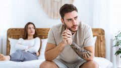 Family crisis and relationship problems. Man and woman feeling stressed and angry at each other, sits on wooden bed and look to side of free space in modern ethnic bedroom interior, panorama