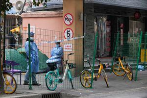 Los trabajadores usan trajes protectores detrás de una barrera en un área sellada luego del brote de la enfermedad por coronavirus (COVID-19), en Shanghái, China, el 11 de octubre de 2022. 