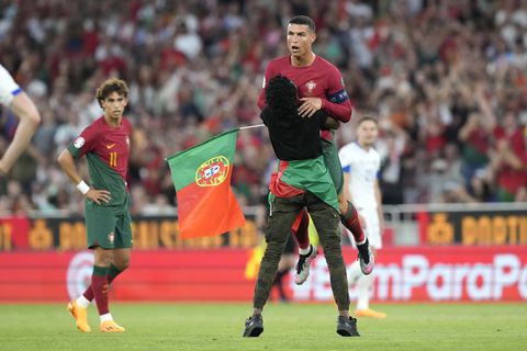 Un invasor de campo atrapa a Cristiano Ronaldo de Portugal durante el partido clasificatorio del grupo J para la Eurocopa 2024 entre Portugal y Bosnia y Herzegovina, en el Estadio Luz de Lisboa, Portugal, el sábado 17 de junio de 2023. (Foto AP/Armando Franca)