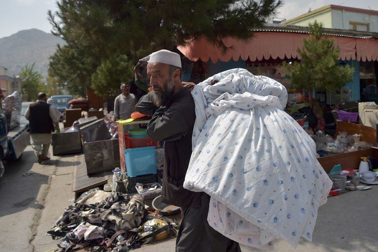 Esta foto tomada el 12 de septiembre de 2021 muestra a un hombre mirando artículos domésticos de segunda mano a la venta en un mercado en el barrio noroeste de Khair Khana en Kabul. - Los mercados de pulgas de Kabul están repletos de pertenencias que afganos desesperados han vendido a precios bajísimos para financiar largos viajes para escapar del país o simplemente para pagar la comida. (Foto de WAKIL KOHSAR / AFP) / PARA IR CON Afganistán-conflicto-mercados de pulgas, FOCUS por James EDGAR