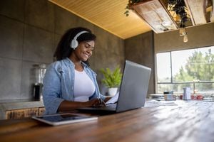 Mujer afroamericana trabajando en casa en su laptop y usando auriculares para una videoconferencia