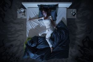 Mujer nerviosa que sufre de insomnio y acostada en la cama a altas horas de la noche, está despierta e inquieta, vista superior