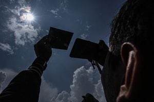 Un hombre usa un espejo protector para observar el eclipse solar en Palembang, Indonesia, el 20 de abril de 2023. El eclipse solar híbrido es un tipo único de eclipse solar que experimenta dos fases simultáneamente, a saber, la fase de anillo y la fase total.