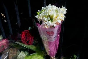 Un ramo de flores con una nota que dice "Lola" se coloca fuera del edificio donde se descubrió el cuerpo de una colegiala de 12 años en un baúl, en París, el miércoles 19 de octubre de 2022. (AP Photo/Michel Euler)