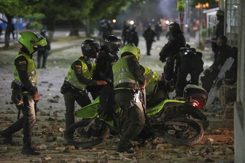 Police aid a fellow officer who slipped on his motorbike during clashes with anti-government demonstrators protesting against the FIFA World Cup Qatar 2022 qualifying soccer match between Argentina and Colombia near the Metropolitano stadium in Barranquilla, Colombia, Tuesday, June 8, 2021. (AP Photo/Jairo Cassiani)