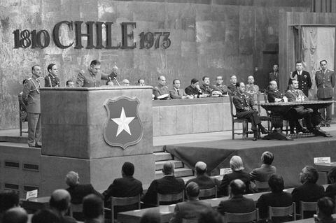 (Original Caption) 10/11/1973-Santiago, Chile- Military junta President General Augusto Pinochet (L) delivers a radio speech, on the one-month anniversary of the military coup that ousted President Salvador Allende.