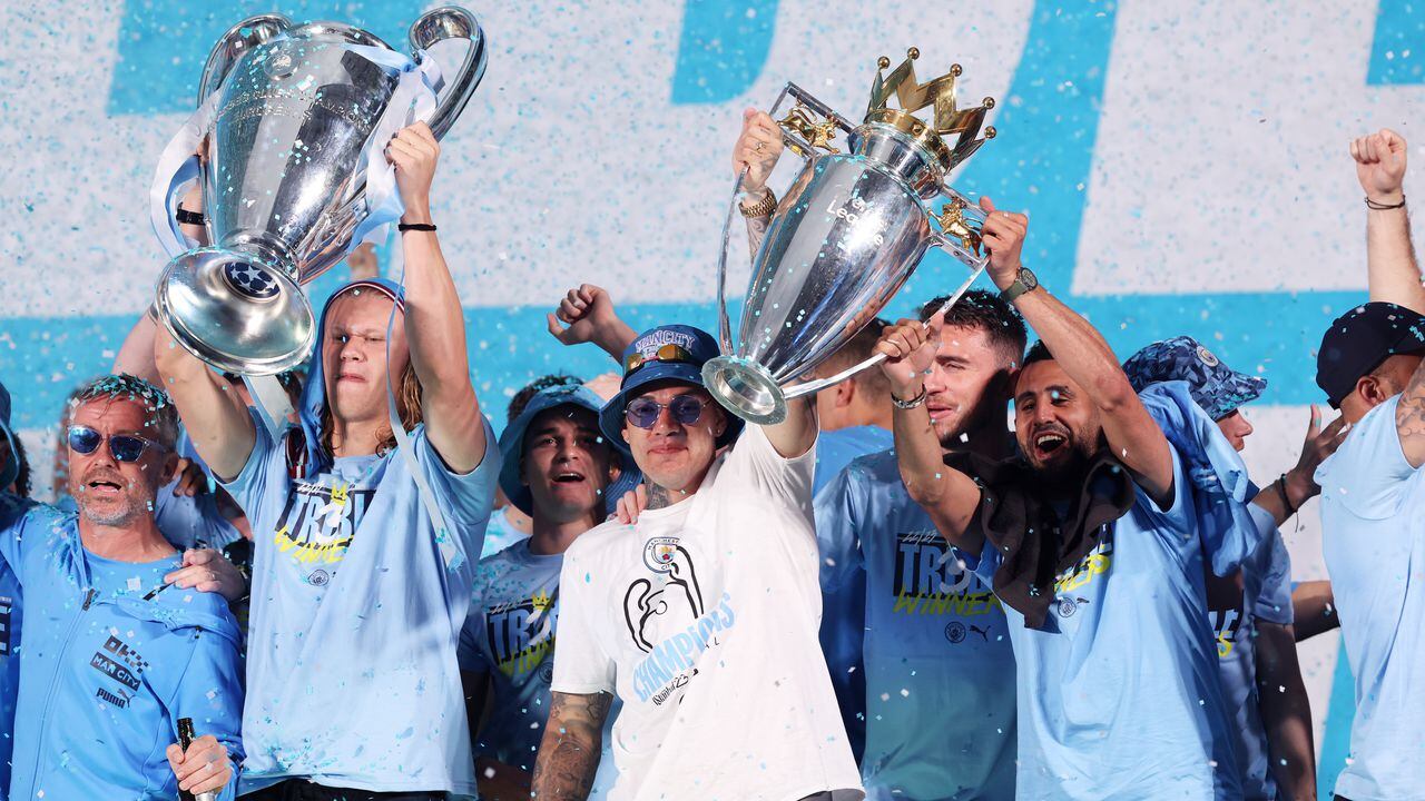 MANCHESTER, ENGLAND - JUNE 12: Erling Haaland lifts the UEFA Champions League Trophy as Ederson and Riyad Mahrez lift the Premier League Trophy on stage in St Peter's Square during the Manchester City trophy parade on June 12, 2023 in Manchester, England. (Photo by Alex Livesey/Getty Images)