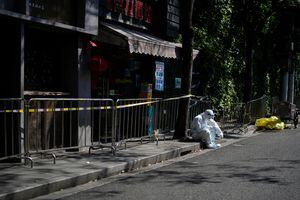 Un trabajador con traje protector descansa en una calle durante un cierre, en medio de la pandemia de la enfermedad por coronavirus (COVID-19), en Shanghái, China, el 17 de abril de 2022. Foto REUTERS/Aly Song