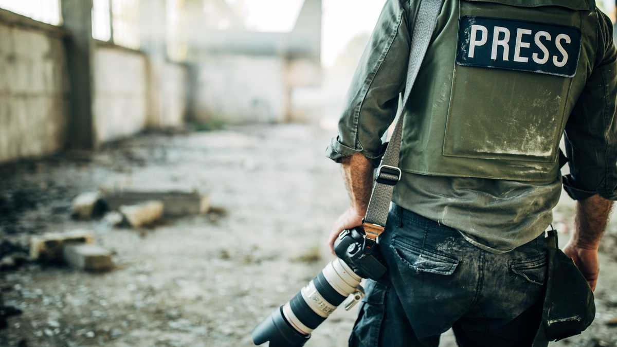 Un hombre, periodista de guerra con cámara digital en el lugar de la acción, en zona de guerra.