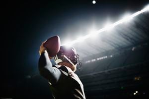 Professional football quarterback preparing to throw pass on stadium field at night