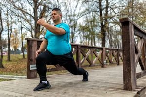 Hombre de talla grande entrenando y corriendo al aire libre. Está haciendo algunos ejercicios cardiovasculares para bajar la barriga.